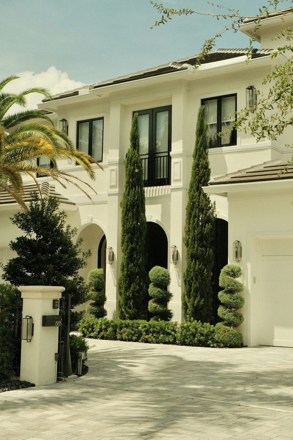 Elegant white home framed by cypress trees